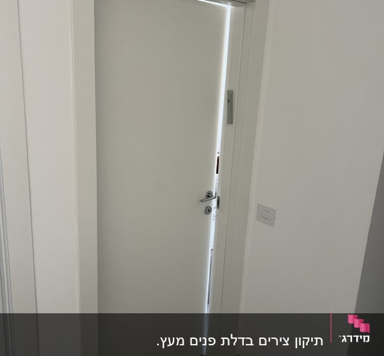 דלת לבנה פתוחה למחצה עם ידית כסופה
